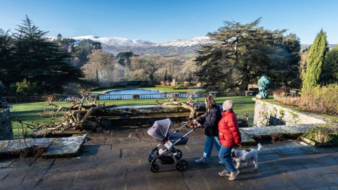 Teulu yn cerdded gyda phram a chi yn mwynhau'r golygfeydd o'r mynyddoedd eiraog